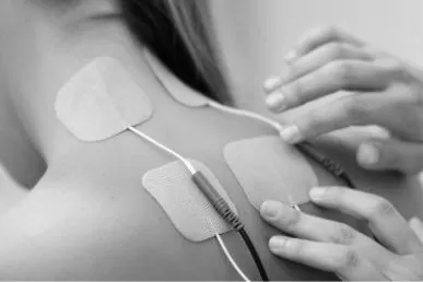 Female patient receiving electrical stimulation treatment on neck and upper back.